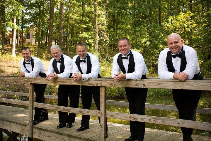 groom and groomsmen standing on bridge